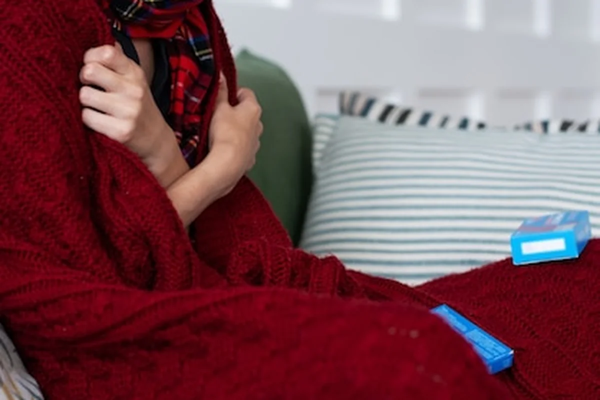 Chora kobieta owinięta w koc z złym samopoczuciem