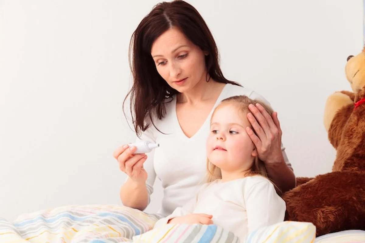 Matka sprawdza temperaturę córki w łóżku