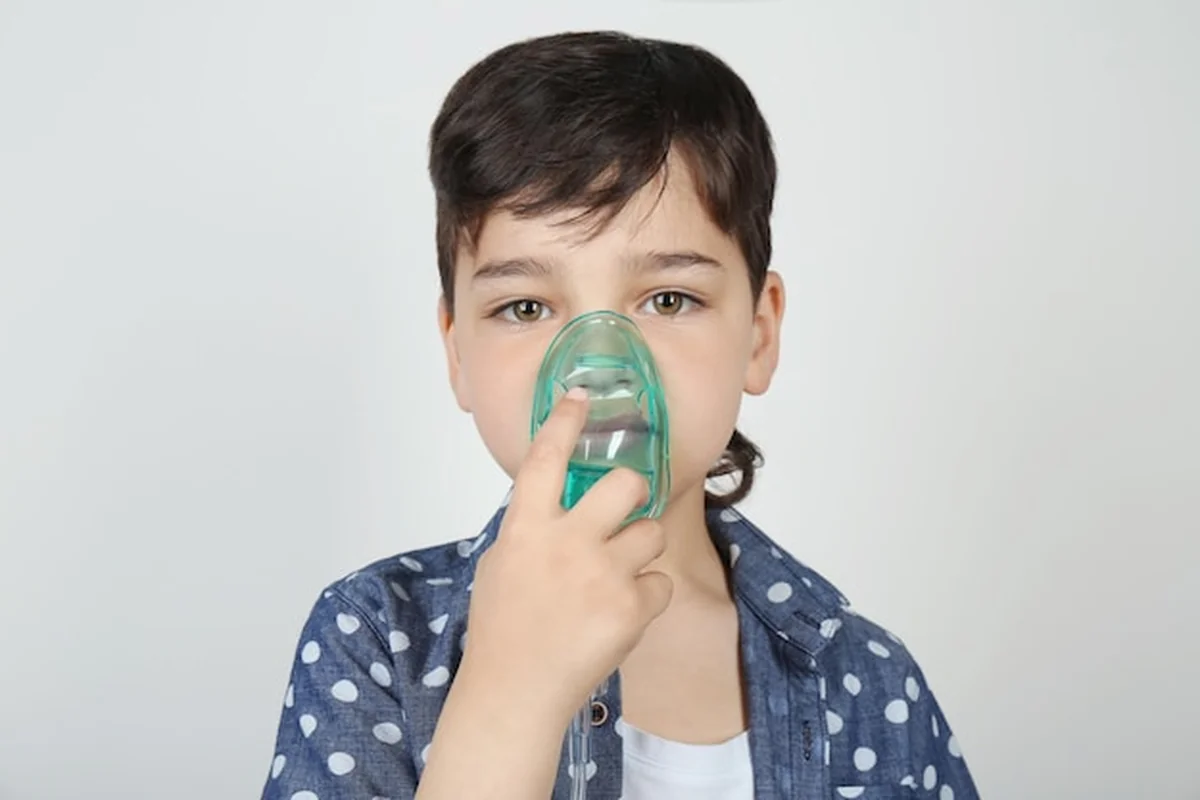 Chłopiec używający maszyny do astmy na jasnym tle