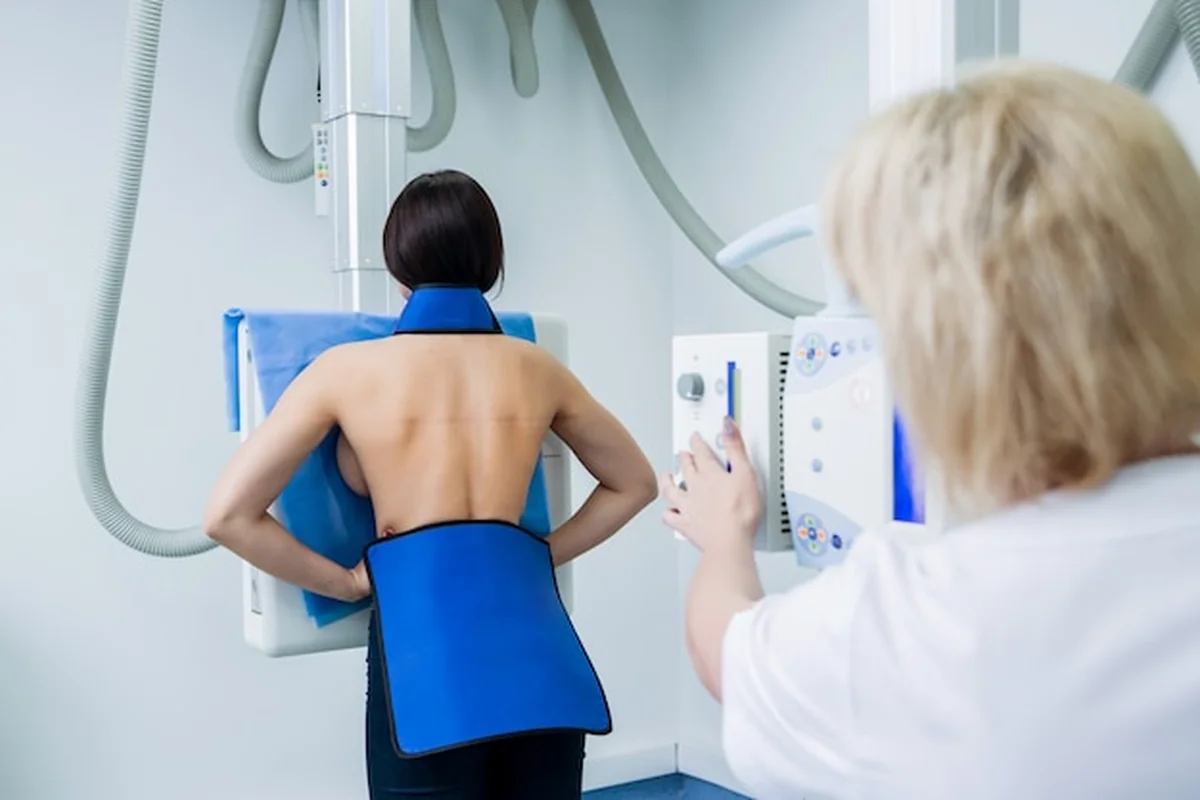 Radiolog i pacjent w pokoju RTG z klasycznym systemem rentgenowskim