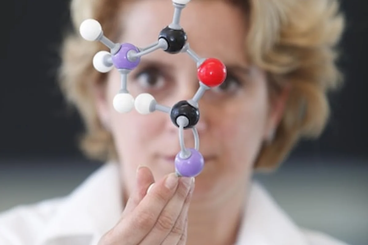 Naukowiec trzymający plastikową strukturę molekularną