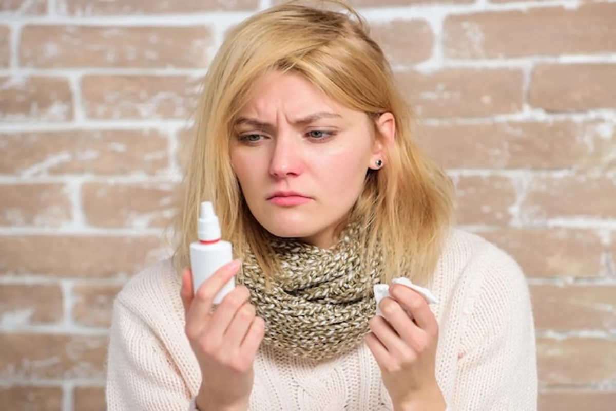 Chora dziewczyna trzyma krople do nosa i tkankę