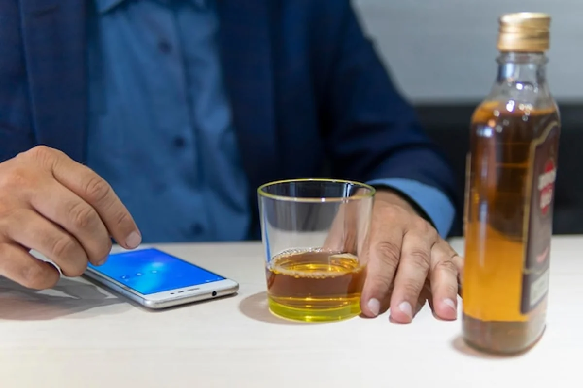 Mężczyzna alkoholik z butelką rumu w ręce w domu