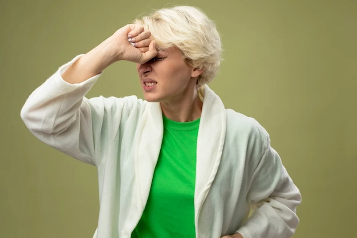 Kobieta z krótkimi włosami dotykająca czoła