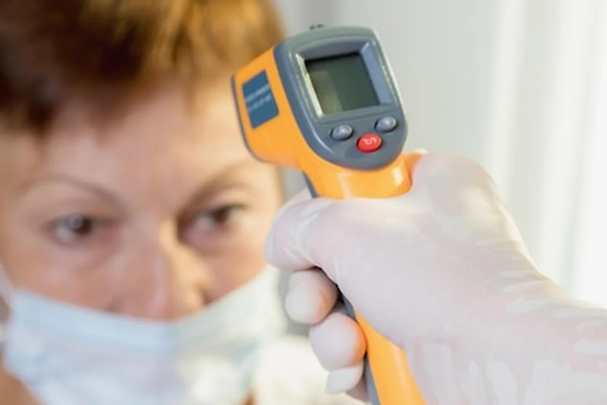 Lekarz mierzy temperaturę laserem u kobiety